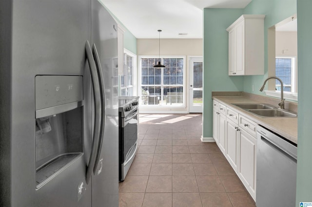 kitchen featuring stainless steel appliances, hanging light fixtures, sink, light tile patterned floors, and white cabinets