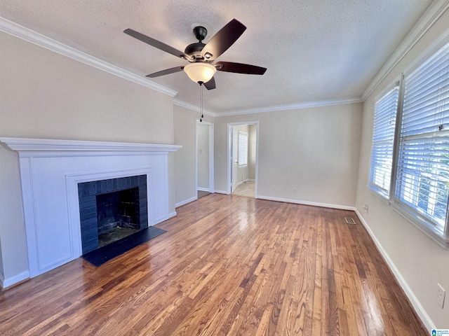 unfurnished living room featuring hardwood / wood-style flooring, ornamental molding, a brick fireplace, and a textured ceiling