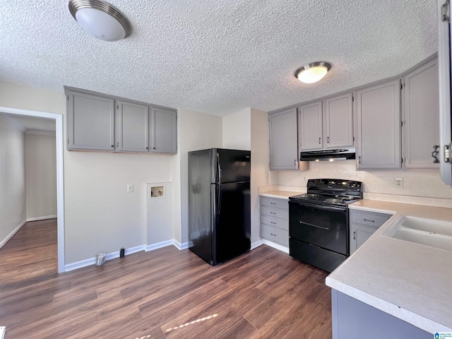 kitchen with sink, dark wood-type flooring, black appliances, and gray cabinetry