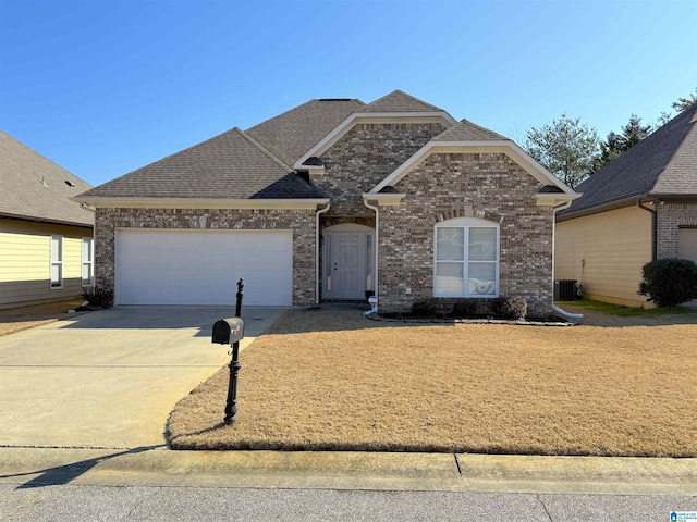 view of front of property with an attached garage, cooling unit, brick siding, a shingled roof, and driveway