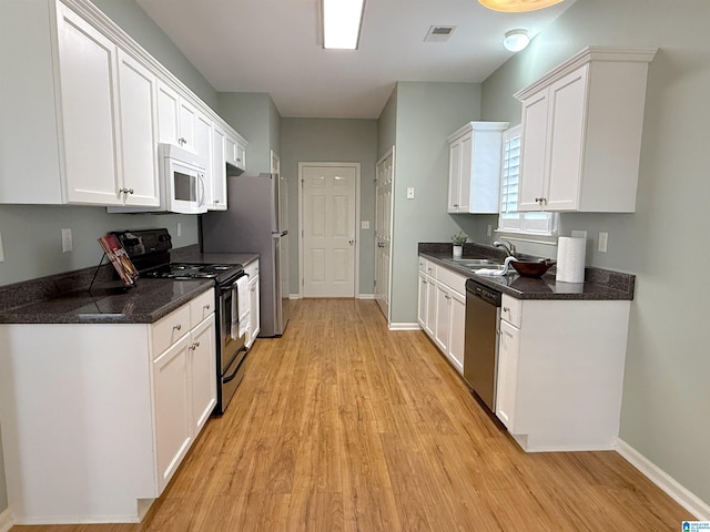 kitchen with visible vents, dishwasher, white microwave, black electric range oven, and white cabinetry