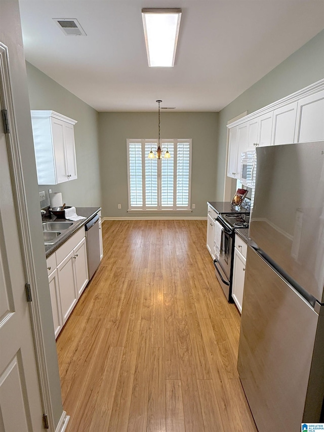 kitchen with hanging light fixtures, appliances with stainless steel finishes, dark countertops, and white cabinetry