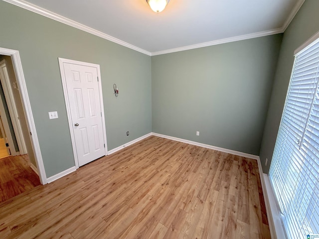 empty room with light wood-style floors, baseboards, and crown molding