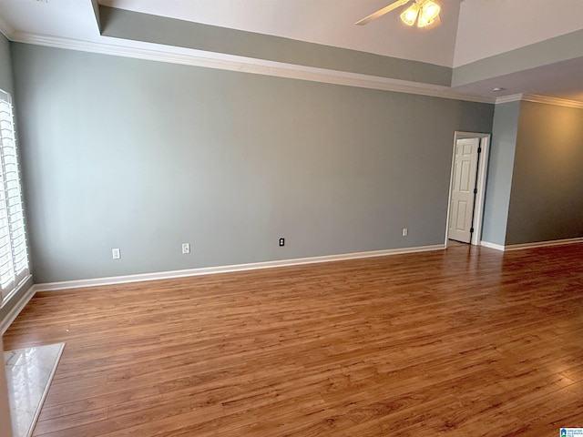 spare room featuring ornamental molding, a ceiling fan, vaulted ceiling, wood finished floors, and baseboards