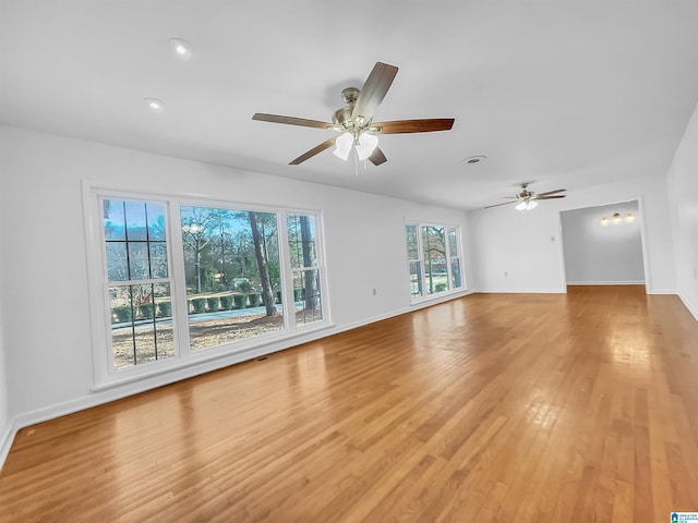 unfurnished living room with a ceiling fan, light wood-style flooring, and baseboards