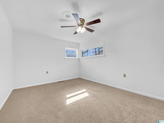 carpeted spare room featuring visible vents, a ceiling fan, and baseboards