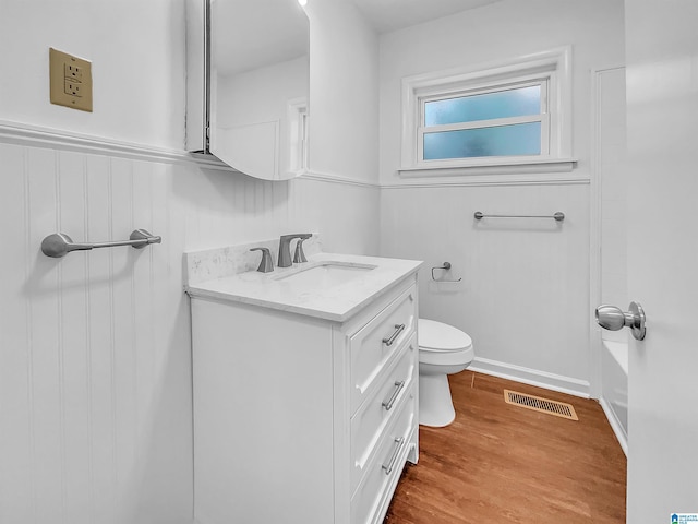 bathroom with visible vents, wainscoting, toilet, wood finished floors, and vanity