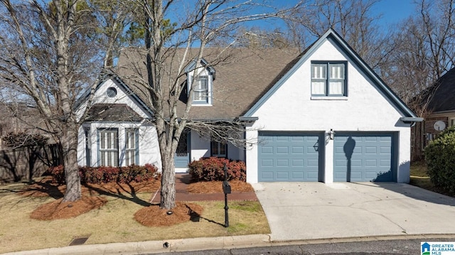 view of front facade with concrete driveway, roof with shingles, and stucco siding