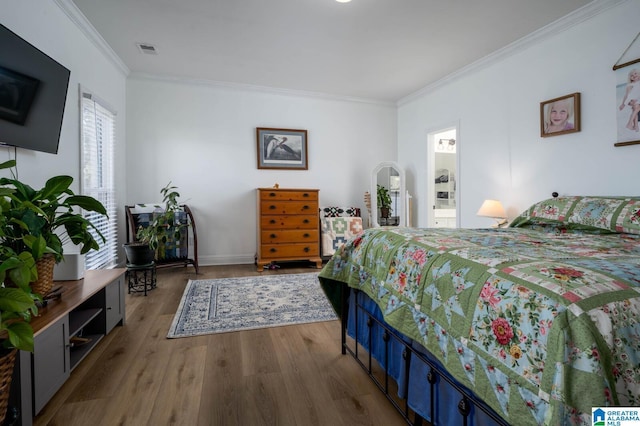 bedroom with light wood-style flooring, visible vents, and ornamental molding