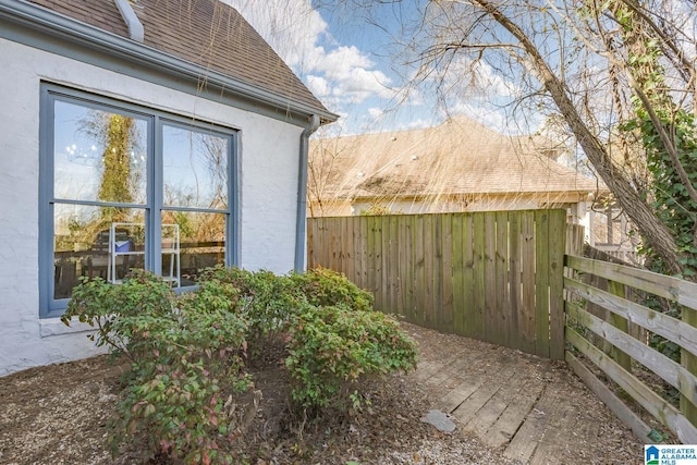 view of home's exterior with roof with shingles, fence, and stucco siding