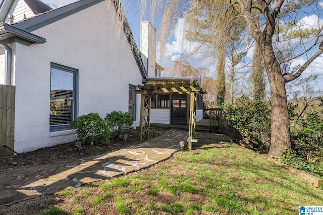 view of side of property with a chimney, a lawn, and stucco siding