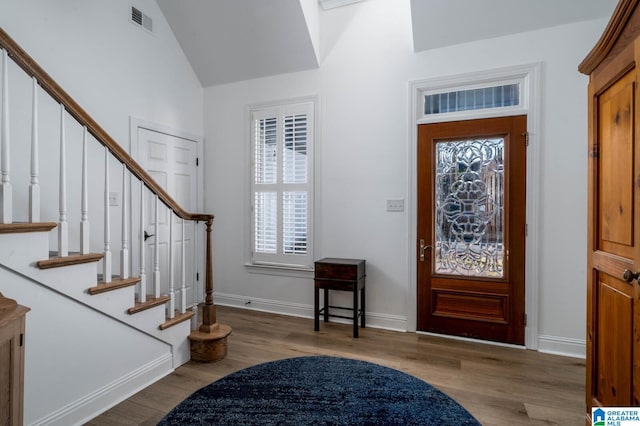 foyer featuring light wood finished floors, visible vents, stairway, vaulted ceiling, and baseboards