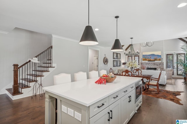 kitchen with white cabinets, pendant lighting, a kitchen island, and dark hardwood / wood-style floors