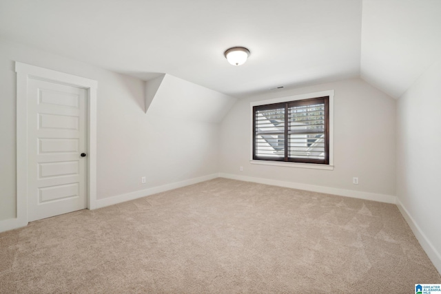 additional living space featuring light carpet and vaulted ceiling