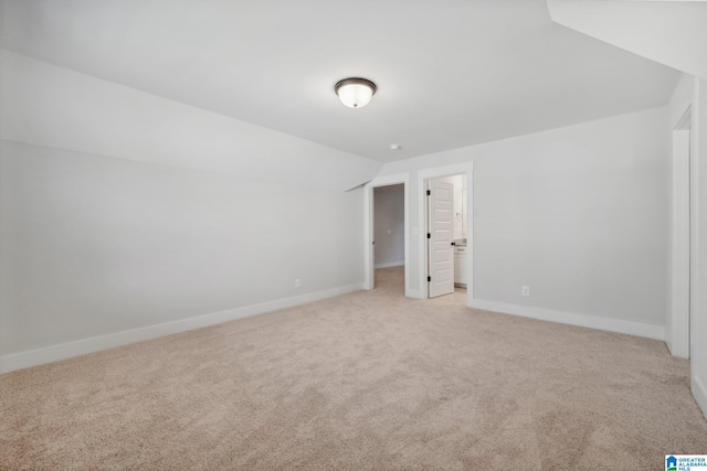 unfurnished bedroom featuring vaulted ceiling, a walk in closet, and light colored carpet