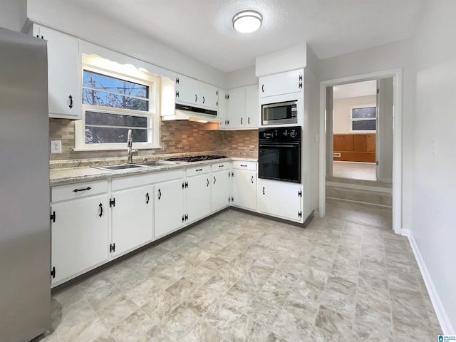 kitchen featuring white cabinetry, stainless steel appliances, sink, backsplash, and light stone counters