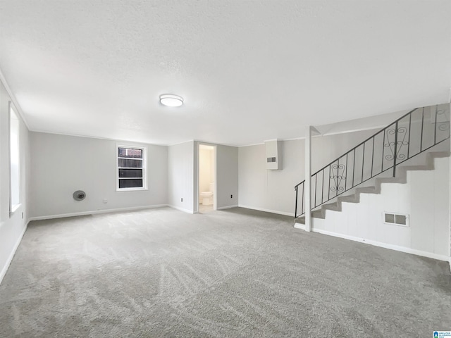 unfurnished living room featuring carpet floors and a textured ceiling