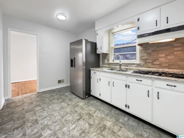 kitchen with appliances with stainless steel finishes, sink, white cabinetry, and tasteful backsplash