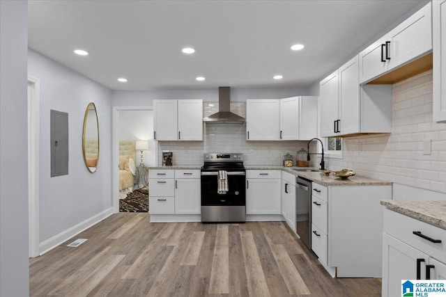 kitchen with appliances with stainless steel finishes, sink, wall chimney exhaust hood, and white cabinets