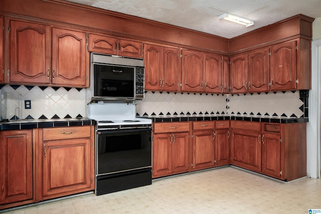 kitchen featuring range with electric stovetop, tile counters, a textured ceiling, and decorative backsplash