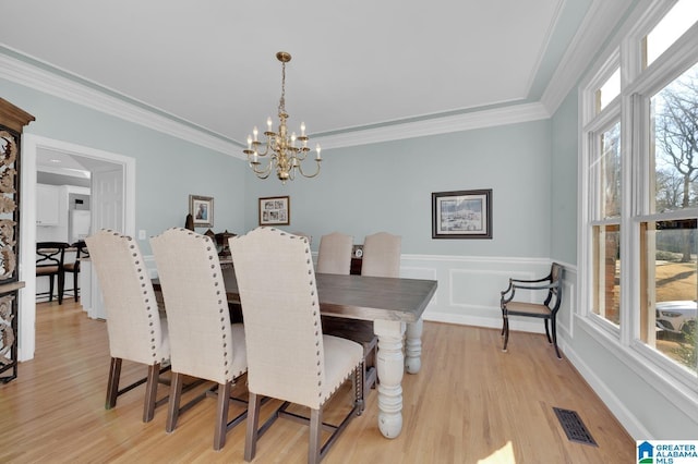 dining room with visible vents, crown molding, a notable chandelier, and light wood finished floors