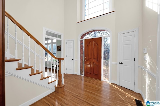 entryway featuring stairs, a high ceiling, wood finished floors, and baseboards