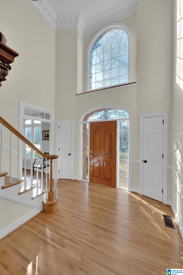 entryway featuring ornamental molding, a healthy amount of sunlight, stairway, and wood finished floors