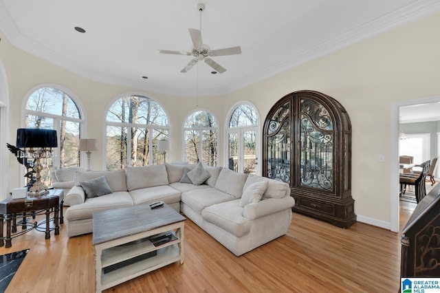 living area featuring light wood-style floors, ornamental molding, baseboards, and ceiling fan