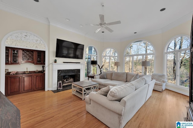 living room featuring light wood finished floors, ornamental molding, and a wealth of natural light