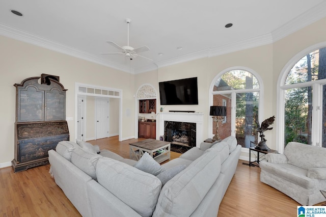 living room with a healthy amount of sunlight, crown molding, light wood finished floors, and a premium fireplace