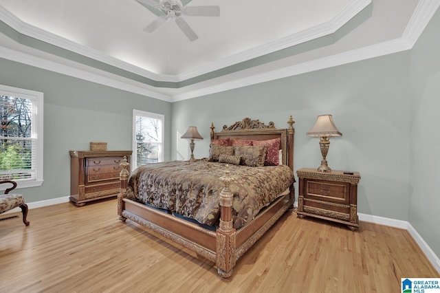 bedroom with light wood finished floors, baseboards, and a raised ceiling