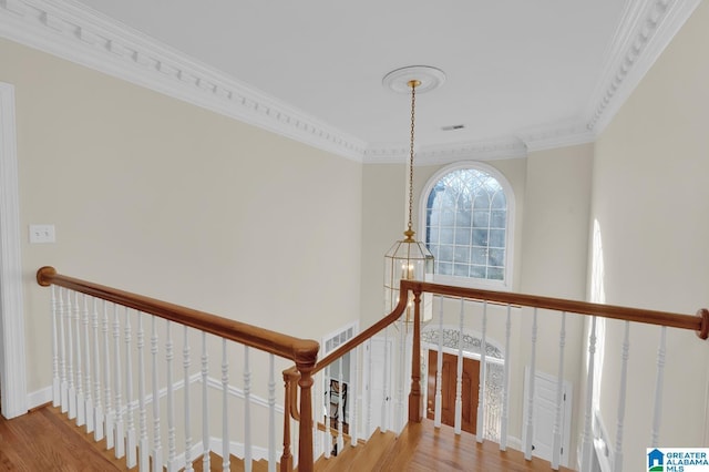 stairway featuring an inviting chandelier, crown molding, baseboards, and wood finished floors