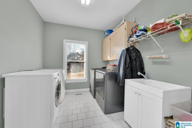 washroom with light tile patterned flooring, cabinet space, baseboards, and separate washer and dryer