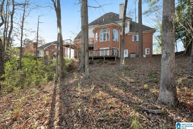 back of house featuring brick siding and a chimney