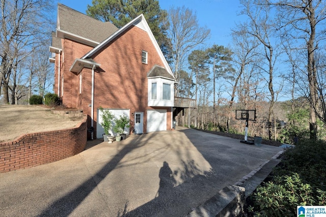 view of side of home with a garage, concrete driveway, and brick siding