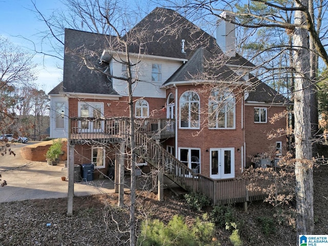 back of property with a chimney, stairs, a deck, a patio area, and brick siding