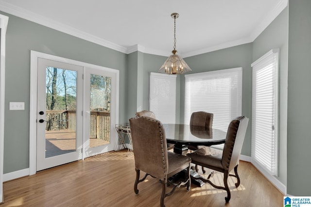 dining room with light wood-style floors, baseboards, a chandelier, and crown molding