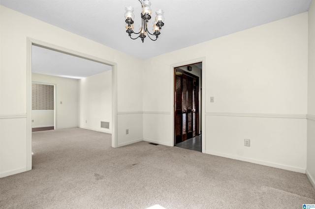 carpeted spare room featuring a chandelier