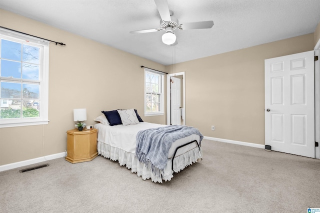 carpeted bedroom with ceiling fan and a textured ceiling