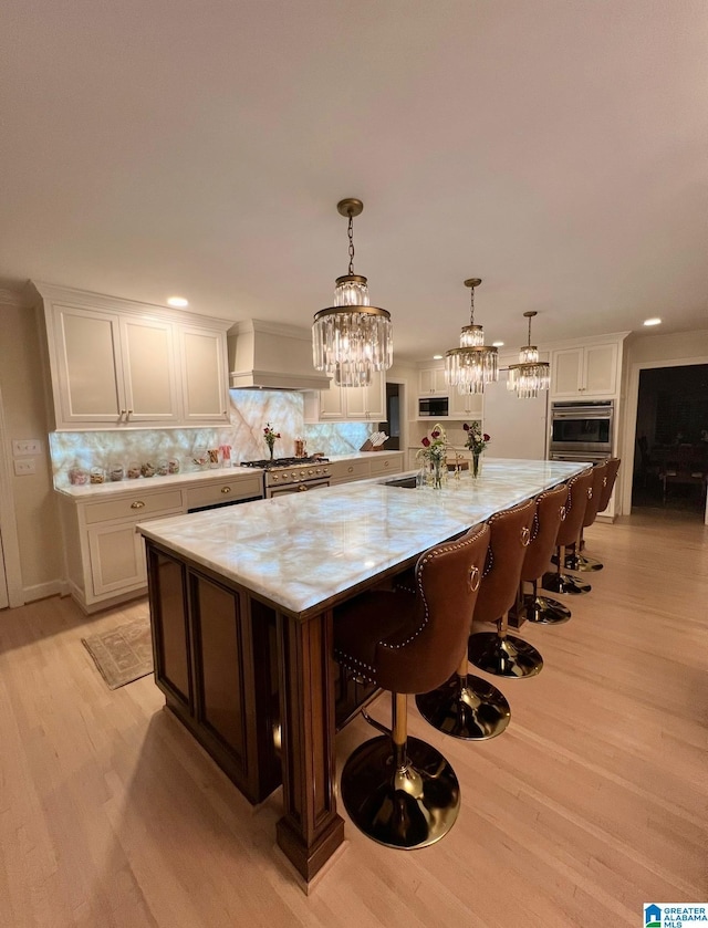 kitchen featuring premium range hood, backsplash, appliances with stainless steel finishes, and white cabinetry