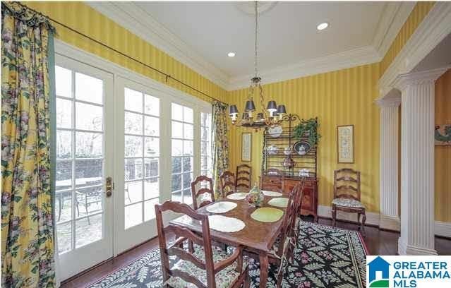 dining space with hardwood / wood-style flooring, ornamental molding, ornate columns, and an inviting chandelier