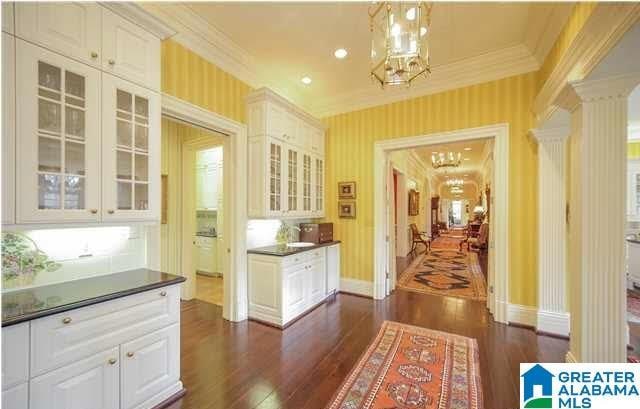 entryway with ornate columns, an inviting chandelier, crown molding, and dark wood-type flooring