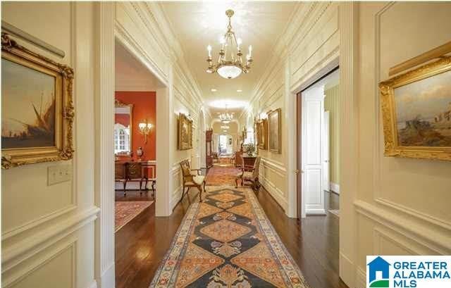 hall with ornamental molding, dark wood-type flooring, and an inviting chandelier