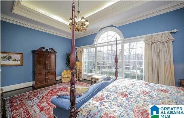 bedroom with crown molding, a raised ceiling, and an inviting chandelier