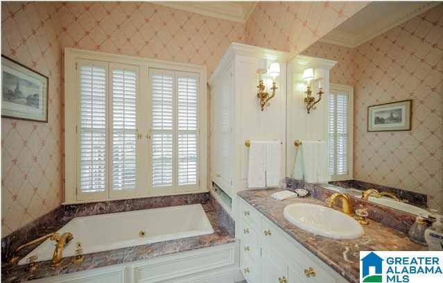 bathroom featuring a washtub, crown molding, and vanity