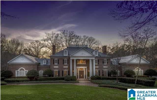 neoclassical home with a chimney and a front lawn