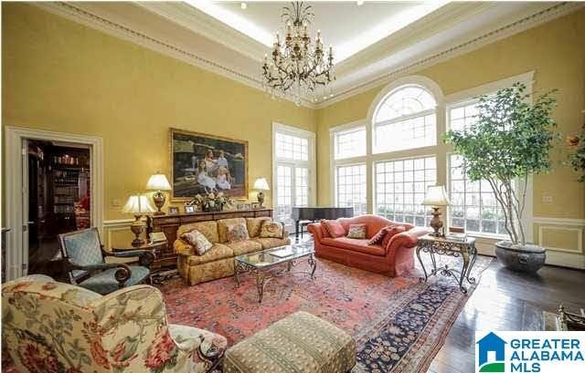 living room featuring a raised ceiling, an inviting chandelier, a high ceiling, and ornamental molding