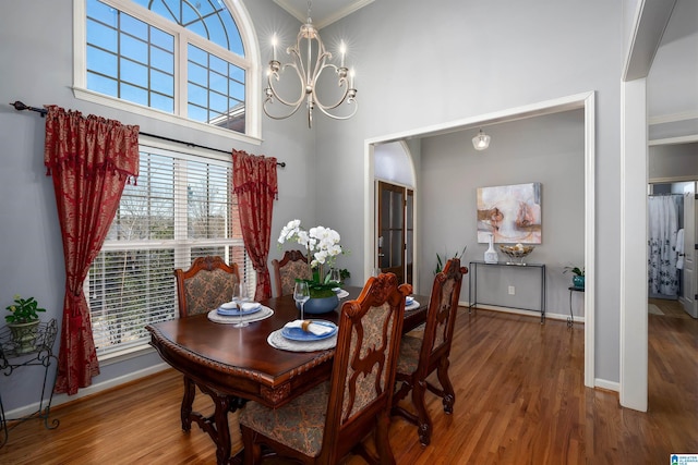 dining room with hardwood / wood-style floors, a chandelier, and a towering ceiling