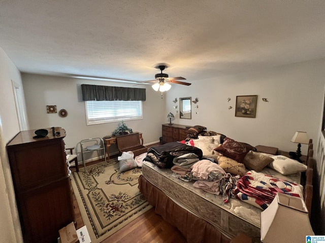 bedroom with hardwood / wood-style flooring, ceiling fan, and a textured ceiling