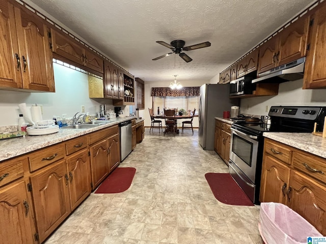 kitchen with appliances with stainless steel finishes, sink, a textured ceiling, ceiling fan with notable chandelier, and hanging light fixtures